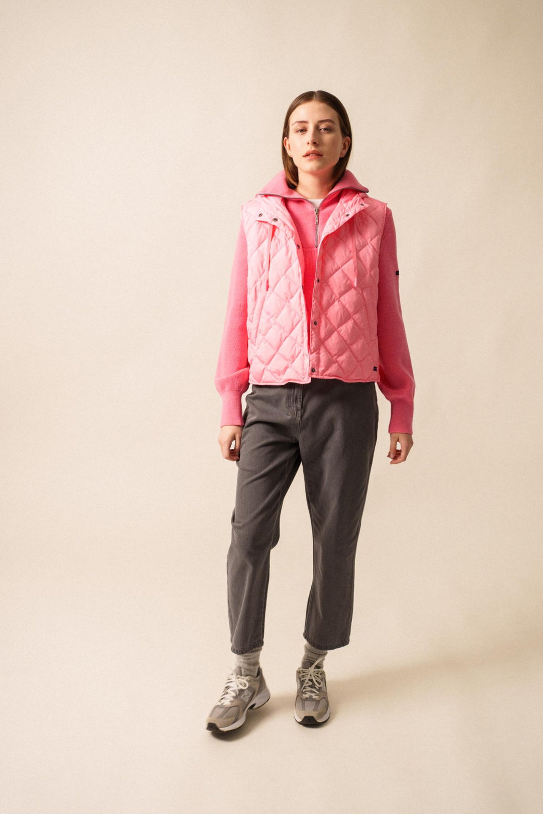 Doudoune sans manche STE JODIE rose, col montant, avec capuche, look sportif et féminin, portée sur un pull.