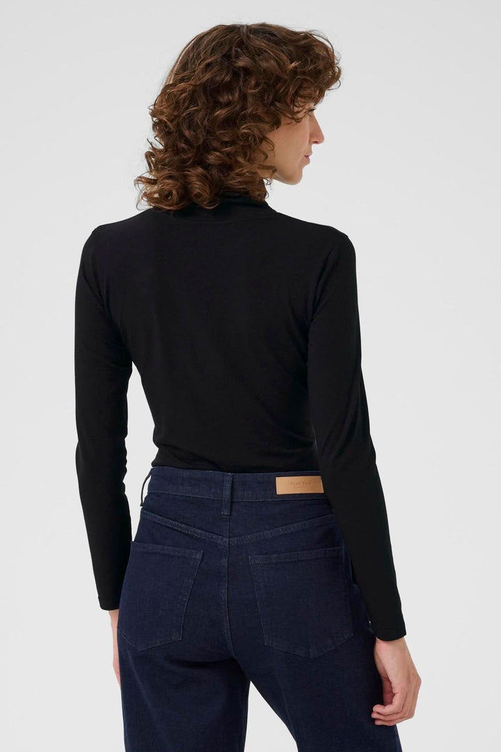 Person wearing Col roulé Efinas, a timeless black turtleneck with long sleeves and a slim fit, showcasing elegant and versatile design.