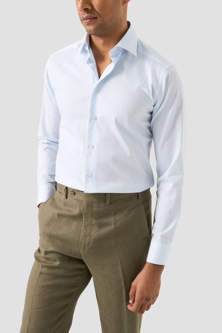 Homme portant une chemise rayée en coton et lyocell bleue, élégante et légère, avec un pantalon décontracté.