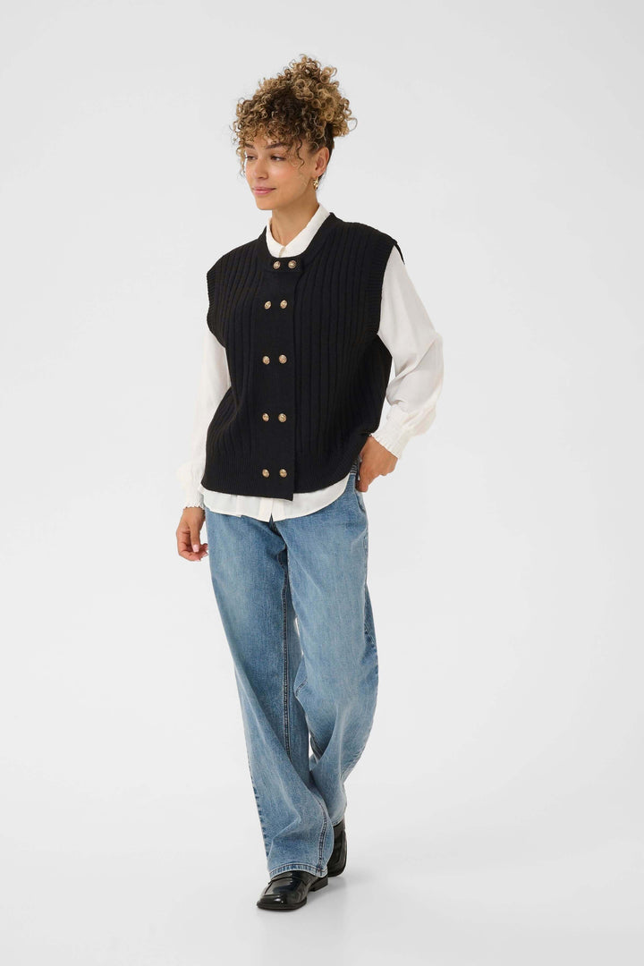 Veste Eroka sans manches en tricot à boutons dorés sur un modèle, chic et polyvalente, parfaite pour mi-saison.