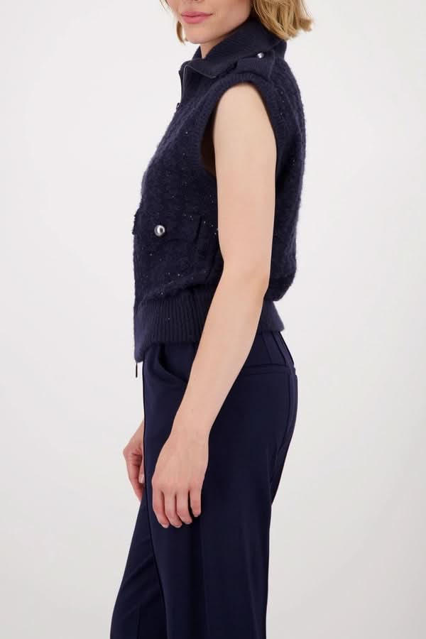 Femme portant une veste sans manches zippée en maille texturée avec poches à rabat et col montant, vue de côté.