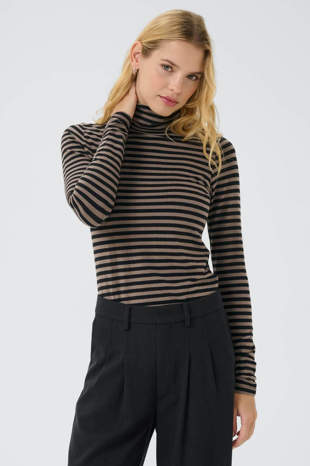 Femme portant un col roulé Efinas rayé noir et marron, manches longues, coupe ajustée, élégance polyvalente et confortable.