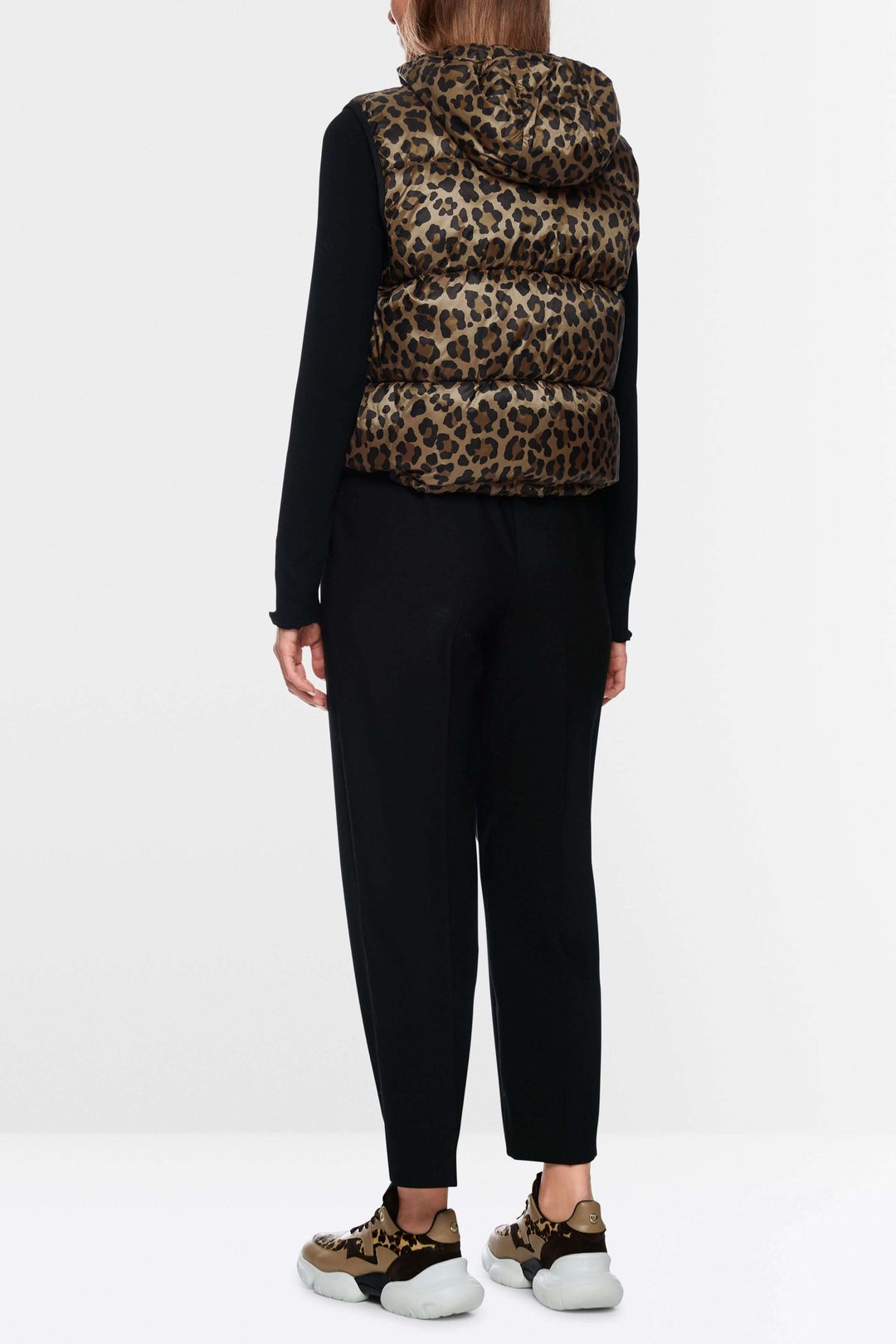 Person wearing a veste matelassée à imprimé léopard et capuchon with black outfit, viewed from the back.