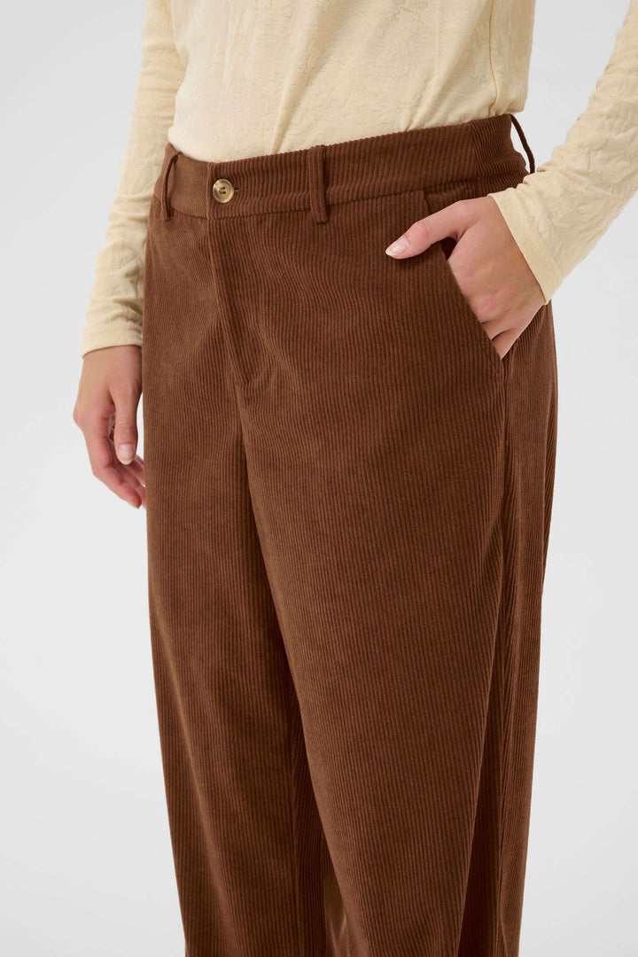 Person wearing "Pantalon Kanna en velours côtelé à jambe large" in brown, showcasing soft textured fabric and wide-leg cut for modern style.