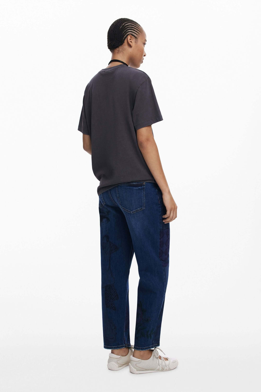 Femme vue de dos portant un t-shirt manches courtes et un jean décontracté, look urbain et moderne.