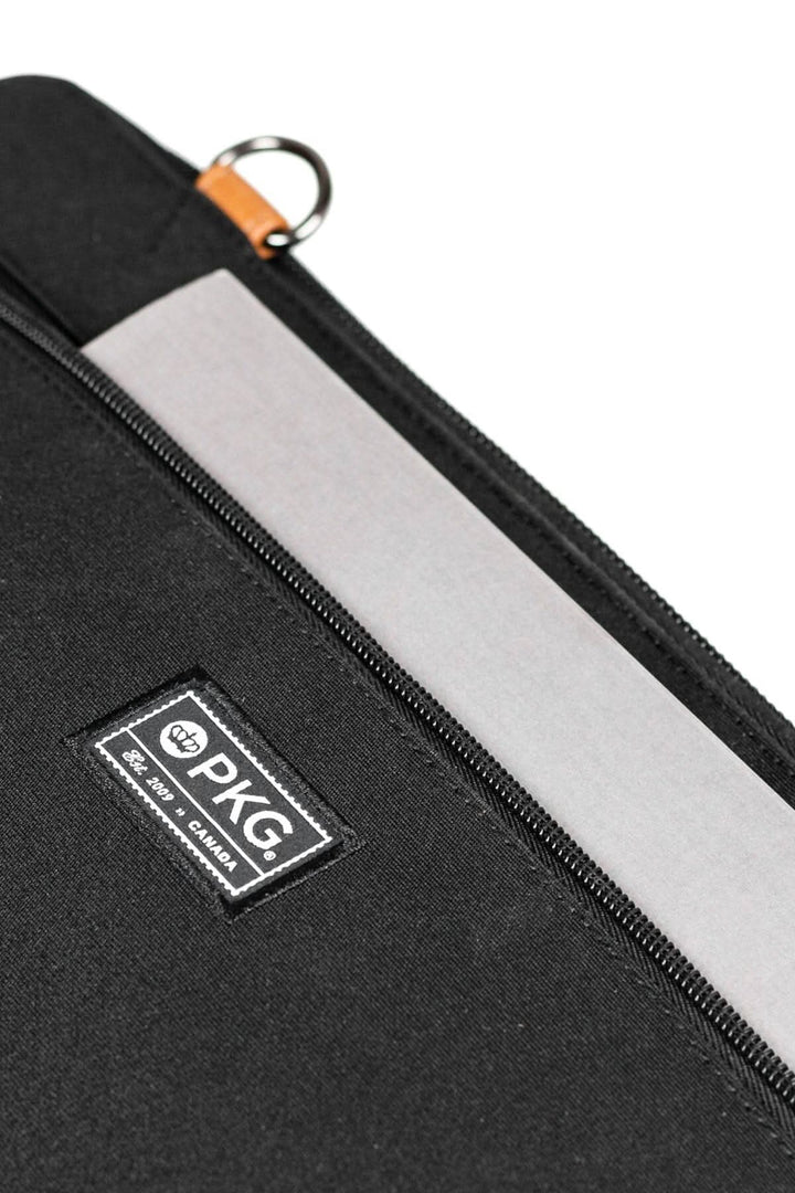 Fermeture éclair du sac messager PKG Wellington 10L avec logo sur un fond en tissu noir.