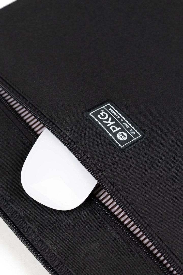 Zoom sur la fermeture éclair du sac messager PKG Wellington 10L avec logo et accessoires à l'intérieur.