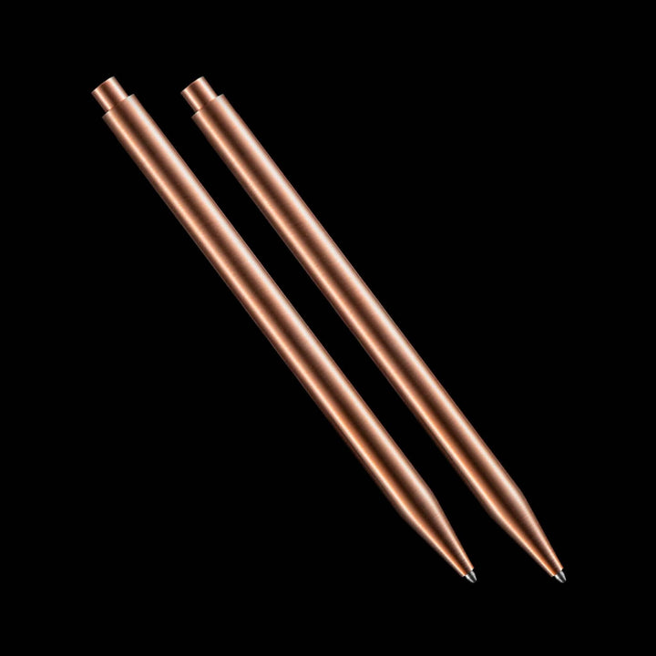 Deux stylos modernes en cuivre sur fond noir, parfaits pour une écriture élégante et contemporaine.
